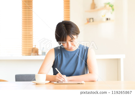 A woman using a touch pen to operate a tablet device 119265867