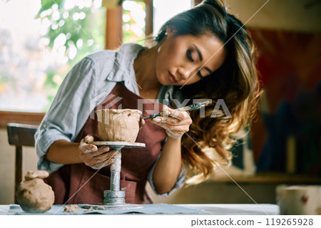 Female artist sculpts crafts with ceramic clay at her creative workshop Female artist sculpts crafts with ceramic clay at her creative workshop 119265928