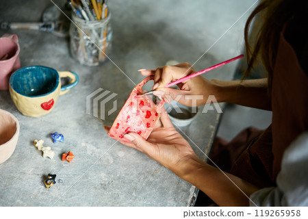 Female artist decorating and painting handmade ceramic clay cup at her creative workshop 119265958
