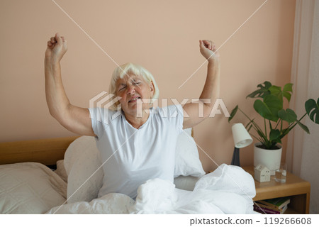 Portrait of beauty Caucasian 50s 60s woman awaking, wake up on the bed. Young beautiful female stretching her arms in fresh early morning, relax peaceful morning routine yawn concept banner 119266608