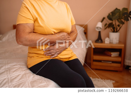 Abdominal pain in elder senior mature aging woman with stomachache illness from stomach cancer. Sick upset senior woman hold belly suffer from abdomen ache concept, mature old adult woman feel morning Abdominal pain in elder senior mature aging woman with stomachache illness from stomach cancer. Sick upset senior woman hold belly suffer from abdomen ache concept, mature old adult woman feel morning 119266638