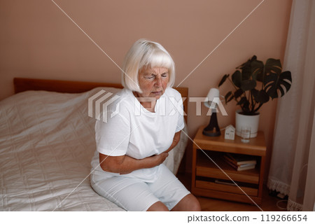 Abdominal pain in elder senior mature aging woman with stomachache illness from stomach cancer. Sick upset senior woman hold belly suffer from abdomen ache concept, mature old adult woman feel morning 119266654