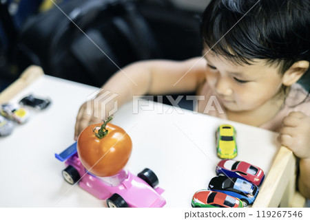 A red ripe round tomato in hand. Hand of little boy holding tomato. 119267546
