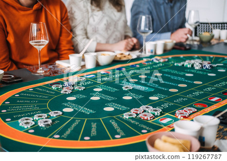 People gathered around a wine-themed casino table with chips and glasses, combining wine tasting and gambling 119267787