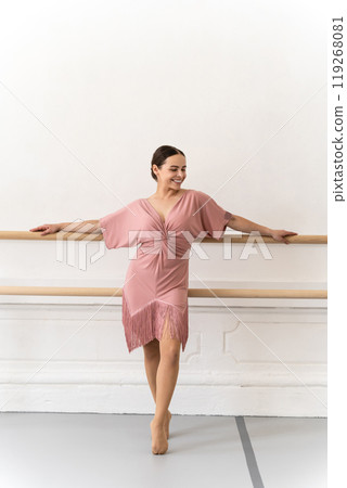 Professional ballerina in beautiful dress practicing indoors at barre during ballet class Professional ballerina in beautiful dress practicing indoors at barre during ballet class 119268081