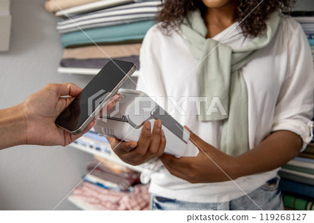 Female customer paying with smart phone in fabric store 119268127