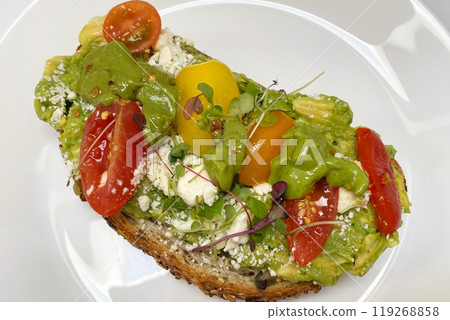 Avocado toast with whole grain bread, cherry tomatoes and feta cheese on a white plate, healthy breakfast food 119268858