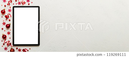 Christmas online shopping from home tablet pc with blank white display top view. Tablet with copy space on colored background with Christmas decorations balls,. Winter holidays sales background Christmas online shopping from home tablet pc with blank white display top view. Tablet with copy space on colored background with Christmas decorations balls,. Winter holidays sales background 119269111