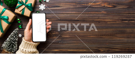 christmas mockup with space for text. christmas advertising, app template. hand holding phone with empty screen on table background. Happy New Year and Xmas Flat lay 119269287