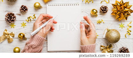 Woman writing Christmas to do list on notebook on colored background with xmas decorations 119269289