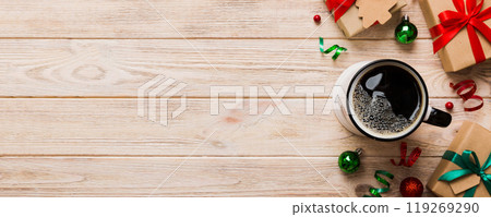 Delicious fresh festive morning coffee in a ceramic cup with little wrapped gifts, ornament and xmas toy. Cup of coffee and new year toys 119269290