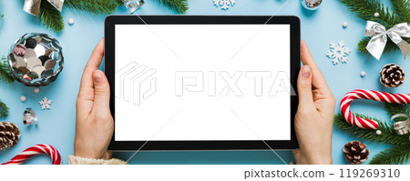 Christmas online shopping from home, female hands holding tablet pc with blank white display top view. woman hand holding tablet with blank screen, Christmas tree and gifts on background Christmas online shopping from home, female hands holding tablet pc with blank white display top view. woman hand holding tablet with blank screen, Christmas tree and gifts on background 119269310