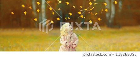 Happy little child having fun playing with flying yellow leaves in autumn park 119269355