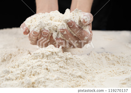 Baker working with white wheat flour, hands close-up. 119270137