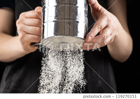 The cook sifts the wheat flour through a metal sieve 119270151