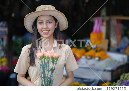 A woman wearing a straw hat and holding a bouquet of flowers 119271235