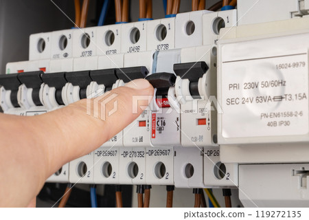 Hand Turning Off Circuit Breaker in Electrical Panel 119272135
