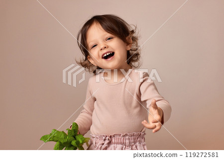 smiling very excited child girl holding fresh green salad on beige background. healthy baby food. 119272581