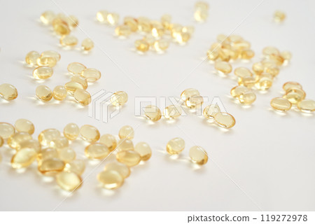 Scattered yellow capsules on white background show health and nutrition Scattered yellow capsules on white background show health and nutrition 119272978