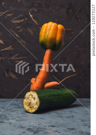 A carrot is standing on top of a zucchini A carrot is standing on top of a zucchini 119273127