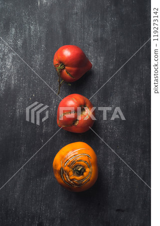 Three tomatoes are shown in a row on a black background Three tomatoes are shown in a row on a black background 119273142