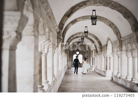 Newly married couple running and jumping while holding hands 119273405
