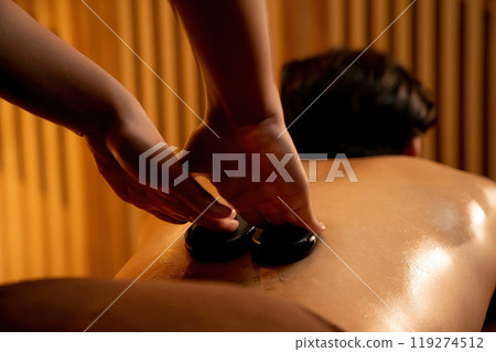 Hot stone massage at spa salon in luxury resort with warm candle light.Quiescent 119274512