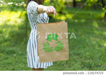 young woman holds an eco-package in her hands on the background of a green lawn, recycling young woman holds an eco-package in her hands on the background of a green lawn, recycling 119274725