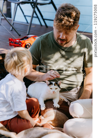 Father and son bonding outdoors with their cat on a sunny day. Memories and enjoying family time 119275008