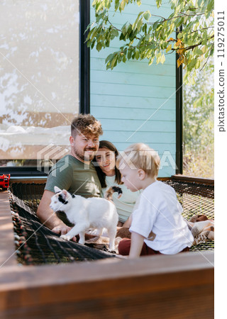 Family enjoying outdoor time with cat, creating precious moments of bonding and relaxation in nature Family enjoying outdoor time with cat, creating precious moments of bonding and relaxation in nature 119275011