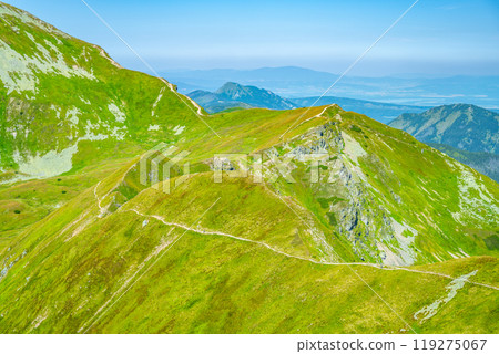 Experience the lush green landscape of the Western Tatras in Slovakia, where winding trails guide hikers through stunning mountain scenery under a clear blue sky. Experience the lush green landscape of the Western Tatras in Slovakia, where winding trails guide hikers through stunning mountain scenery under a clear blue sky. 119275067
