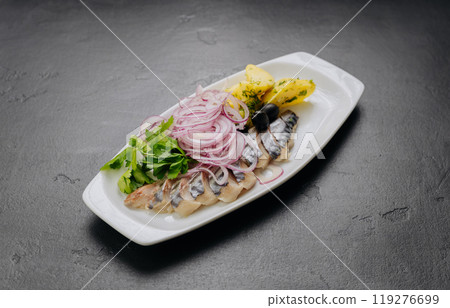 Traditional marinated herring with onion, potatoes and herbs on plate. Perfect for seafood lovers 119276699