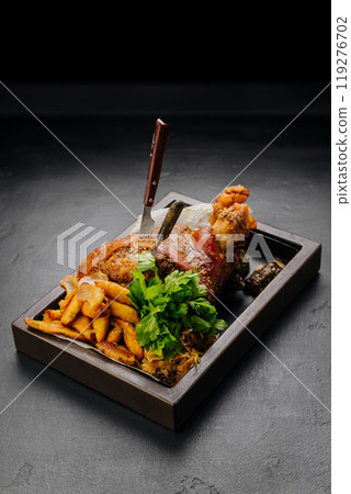 Juicy roasted pork knuckle served with herbs and vegetables on a dark background Juicy roasted pork knuckle served with herbs and vegetables on a dark background 119276702