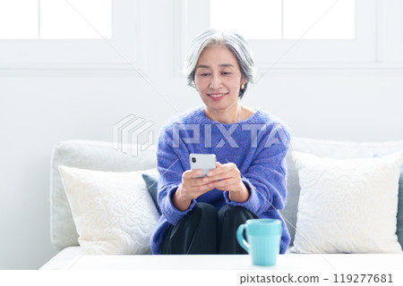 Middle-aged woman using a smartphone in the living room 119277681