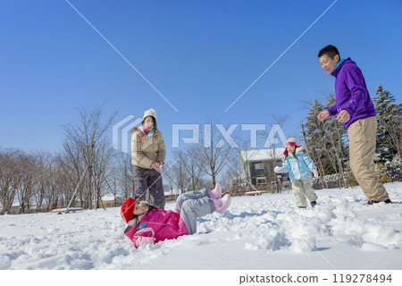A family of four playing in a snowy park 119278494