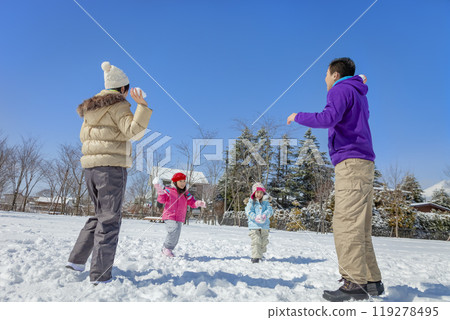 A family of four playing in a snowy park 119278495