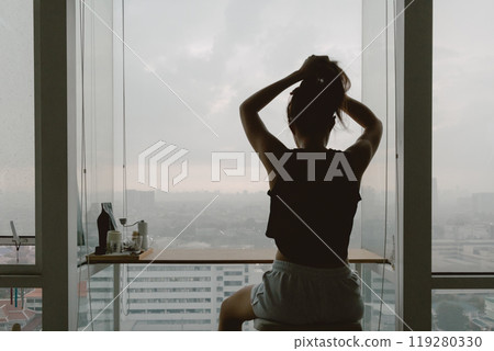 Woman relaxed at her windows apartment, enjoy the view and time. 119280330