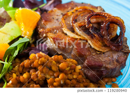 Dish of tasty cooked fried pork with lentils avocado and orange at plate 119280940