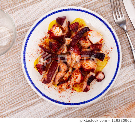 Boiled octopus tentacles with potatoes seasoned with smoked paprika 119280962