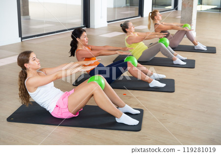 Women exercising with ball during group pilates class 119281019
