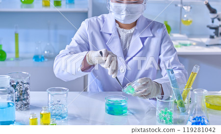 Laboratory scene photography with a female researcher is doing an experiment with hydrogel balls on white lab table with many experiment glassware displayed on 119281042