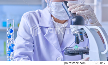 Close up front view shot at a female scientist scientist is using microscope to observe a blue gel ball. Copy space for adding text and elements of design Close up front view shot at a female scientist scientist is using microscope to observe a blue gel ball. Copy space for adding text and elements of design 119281047