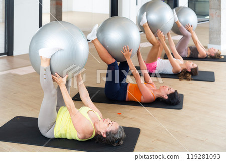 Women doing pilates workout on fitness ball at gym 119281093