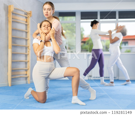 Young woman performing chokehold on female partner during self-defense training Young woman performing chokehold on female partner during self-defense training 119281149
