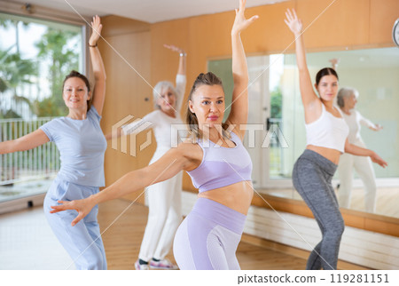 Women dancing synchronous group choreography in dance hall 119281151