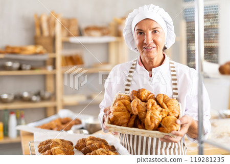 Portrait of joyful elderly woman baker with croissants Portrait of joyful elderly woman baker with croissants 119281235