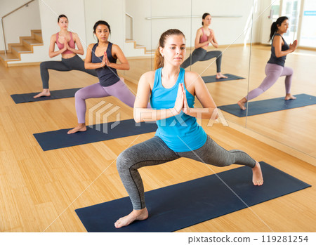 Girl doing twisting asana Parivritta Parsvakonasana in yoga studio Girl doing twisting asana Parivritta Parsvakonasana in yoga studio 119281254