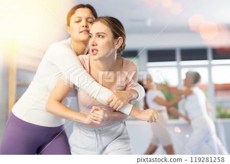 Woman and girl in gym perform basic elements of krav maga self-defense system. 119281258
