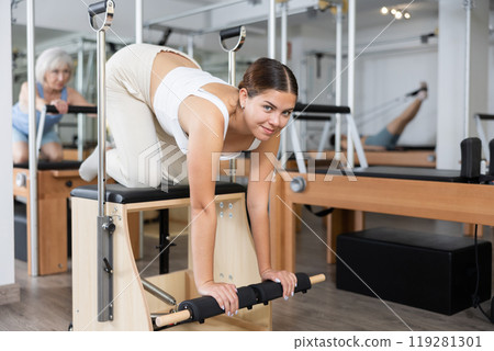 Young girl practicing pilates stretching exercises on combo chair 119281301
