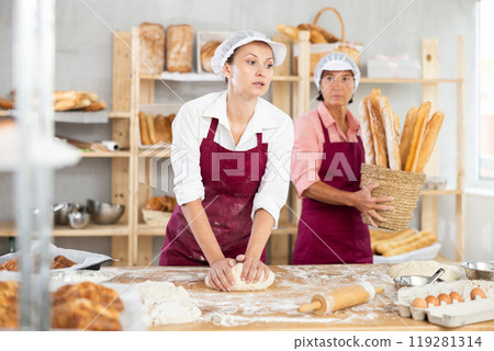 Female baker in maroon apron kneading dough in bakery Female baker in maroon apron kneading dough in bakery 119281314